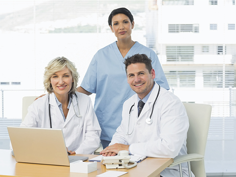 Smiling doctors with laptop at medical office