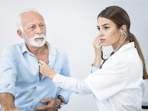 Young female doctor listening to senior man's heartbeat with stethoscope